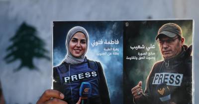 Membro da União de Jornalistas do Líbano segura as fotografias de dois jornalistas mortos.