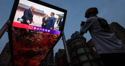 Visita de Donald Trump à China acompanhada através de ecrãs gigantes.