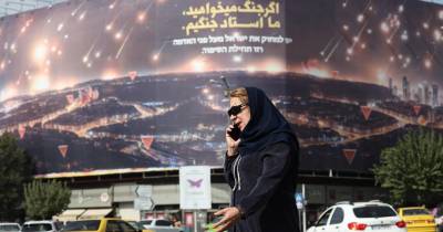 Mulher caminha em frente a um painel anti-Israel, no Irão.